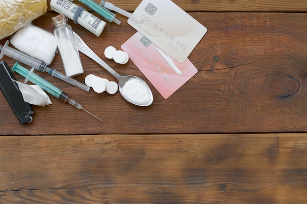 A lot of narcotic substances pills and devices for the preparation of drugs lie on an old wooden table