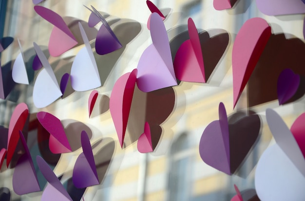 A lot of pink, purple and white paper hearts decorate the window of the house