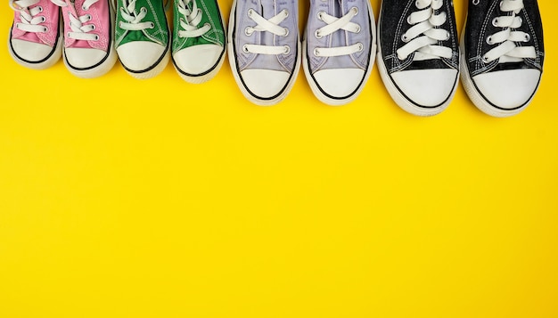 Lot of textile worn sneakers of different sizes on a yellow background