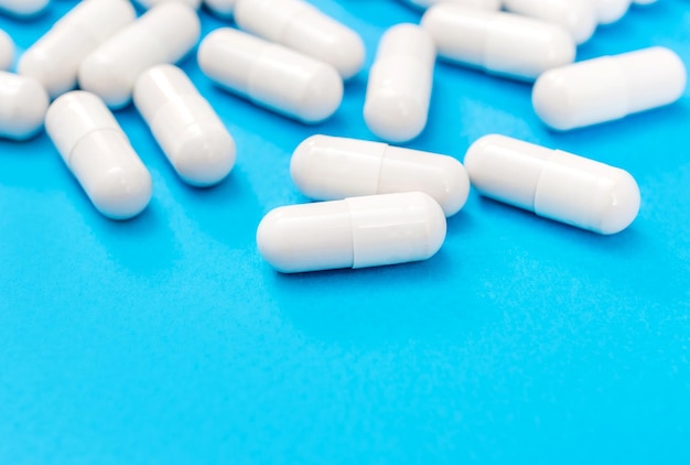 Lot of white capsules on a blue background Medical background