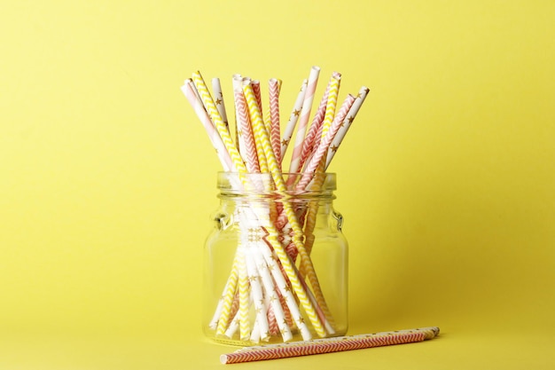 A lot of yellow paper straws in a large bottle on a background. Top view. Place for text. Party concept.