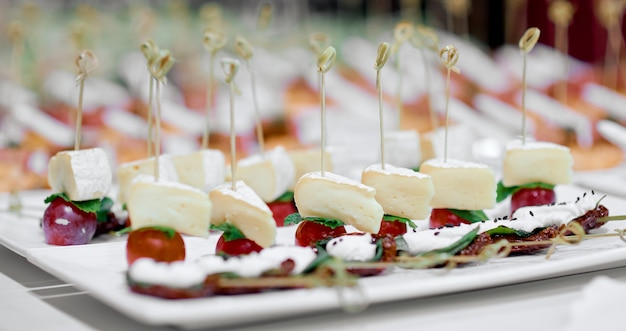 Lots of canapes on white trays on a white table. High quality photo