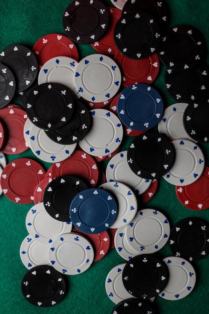 Lots of colorful casino poker chips lie on a green velvet gaming table. Background for gambling.