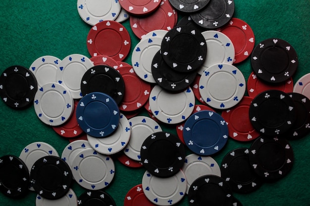 Lots of colorful casino poker chips lie on a green velvet gaming table. Background for gambling.