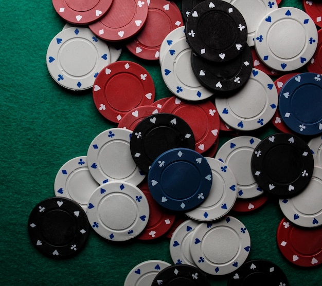 Lots of colorful casino poker chips lie on a green velvet gaming table. Background for gambling.