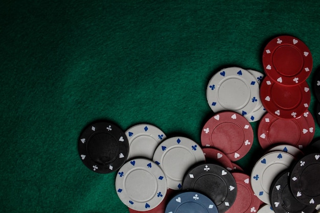 Lots of colorful casino poker chips lie on a green velvet gaming table. Background for gambling.