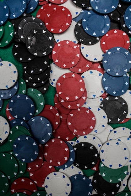 Lots of colorful casino poker chips lie on a green velvet gaming table. Background for gambling.