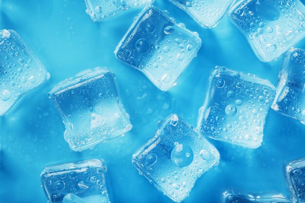 Lots of ice cubes with water drops scattered on a blue background