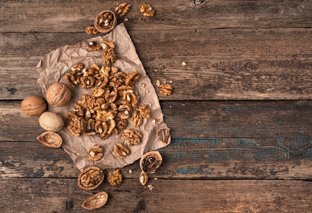 Lots of peeled and whole nuts on a wooden surface