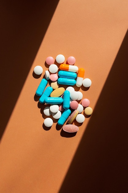 Lots of pills and tablets blue pink yellow and white colors on brown background