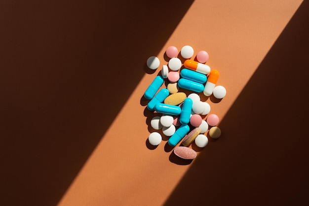 Lots of pills and tablets blue pink yellow and white colors on brown background