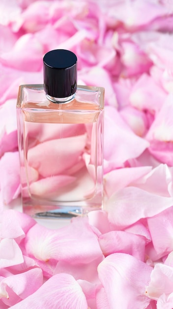 Lots of pink rose petals with a bottle of floral perfume on the table close-up.