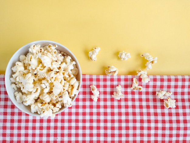 lots of popcorn inside the bowl on top of the checkered cloth top view