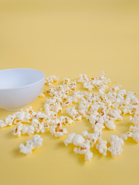 lots of popcorn scattered on the yellow backdrop with empty bowl