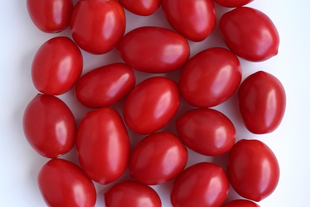 Lots of red conical tomatoes on a white background fresh harvest top view