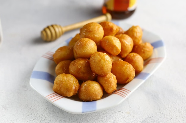 Loukoumades luqaimat or lokma with honey sauce in a plate with white background