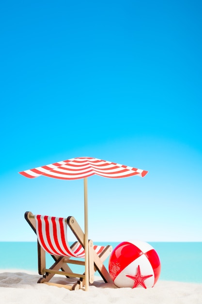 Lounge chair with parasol and beach ball on the coast, sky with copy space