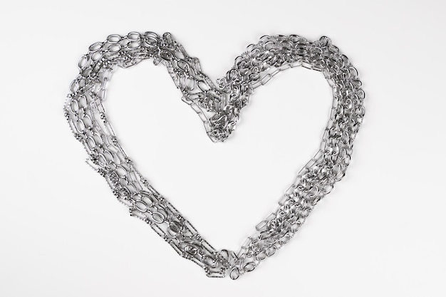 Love Addiction Heart frame made from a stell chain on pink surface Abusive relationship concept