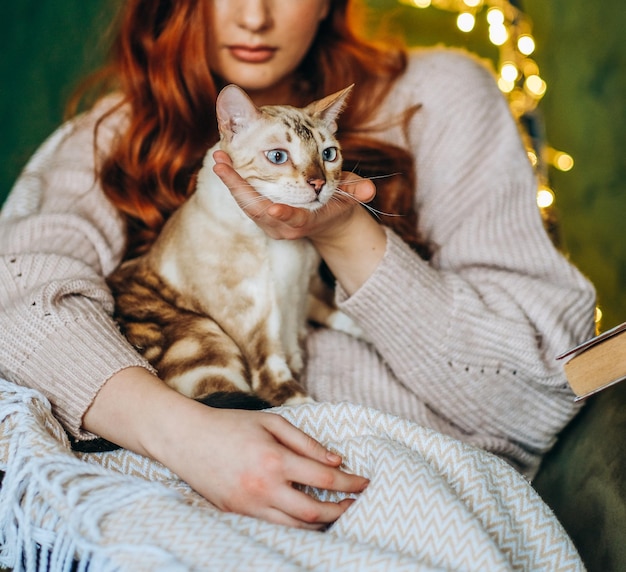 Love for cats A woman sits in a chair at home and holds her beloved Bengal cat in her arms