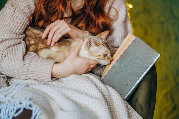 Love for cats A woman sits in a chair at home and holds her beloved Bengal cat in her arms