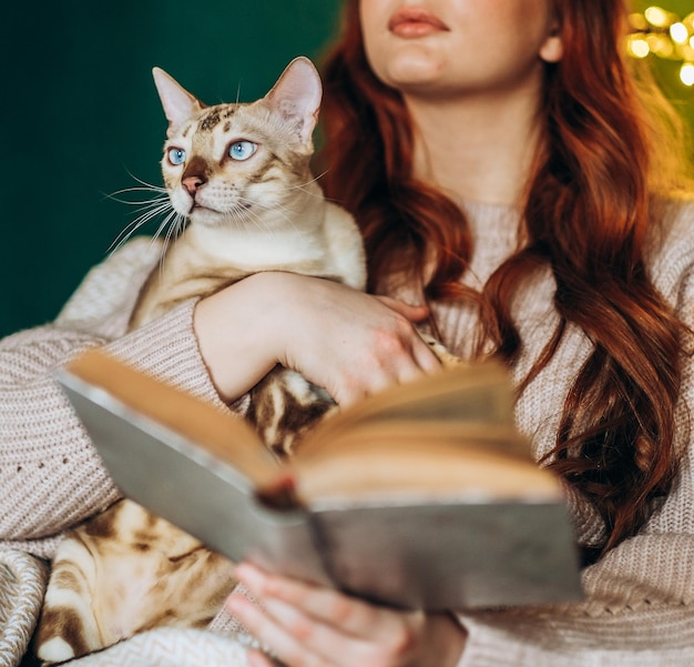 Love for cats A woman sits in a chair at home and holds her beloved Bengal cat in her arms