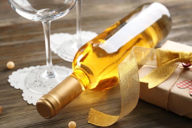 Love concept - wine bottle and gift on wooden background, close up