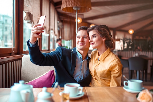 Love couple hugs and makes selfie on phone camera