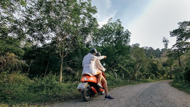 Photo love couple on red motorbike in white clothes to go on forest road trail trip two caucasian tourist