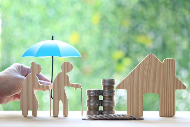 Love couple senior and model house with stack of coins money on natural green background