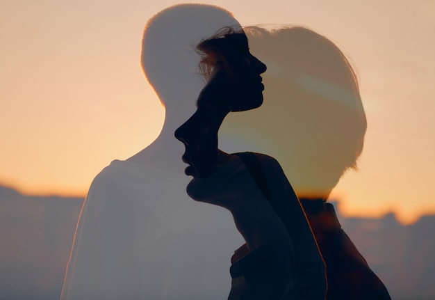 Love of couple young man and woman multiple exposure silhouettes at sunset