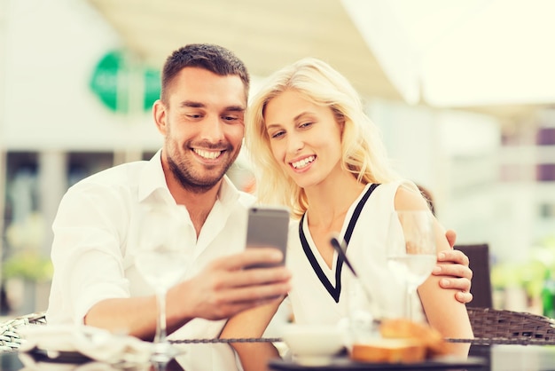 love, date, technology, people and relations concept - smiling happy couple taking selfie with smatphone at city street cafe