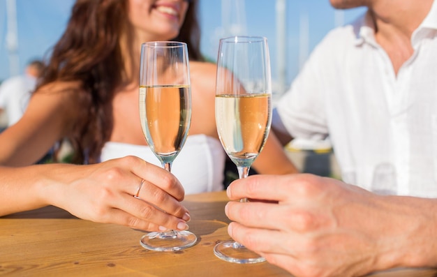 love, dating, people and holidays concept - smiling couple wearing sunglasses drinking champagne and looking to each other at cafe