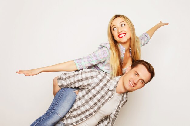 Love, family and people concept: lovely couple, young man carrying girlfriend on his back.