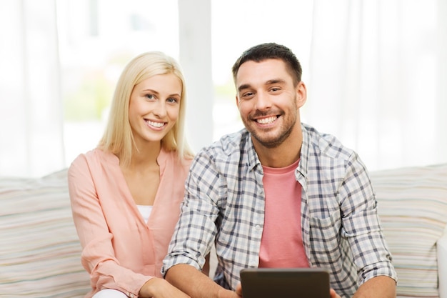 love, family, technology, internet and happiness concept - smiling happy couple with tablet pc computer at home