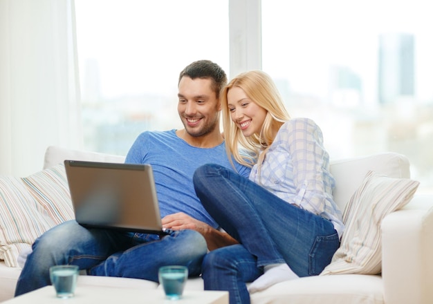 love, family, technology, internet and happiness concept - smiling happy couple witl laptop computer at home