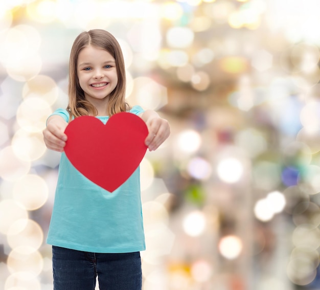 Photo love, happiness and people concept - smiling little girl giving red heart