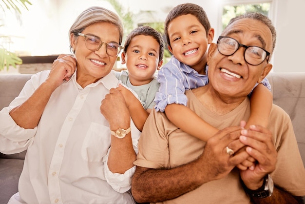 Love happy family and kids relax with grandparents on a sofa hug and bonding in a living room Portrait seniors and children embracing laughing and enjoying visit to grandma and pa on the weekend