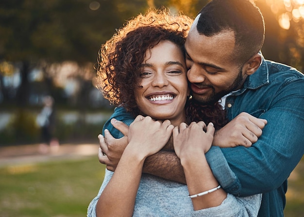 Love hug and couple in park smile and joy with romance bonding and relationship with happiness Portrait partners or man with woman embrace outside or marriage with wellness loving or carefree