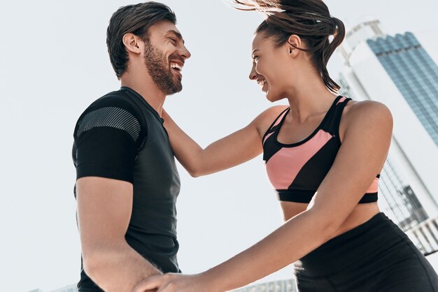 Love inspires them. Beautiful young couple in sport clothing bonding and smiling while standing outside