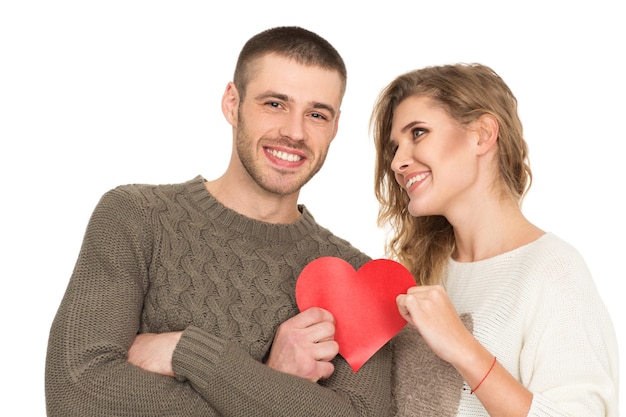 Love is a gift. Portrait of a beautiful happy couple holding red paper heart smiling joyfully isolated on white