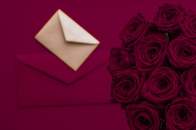 Love letter and flowers delivery on Valentines Day luxury bouquet of roses and card on maroon background for romantic holiday design