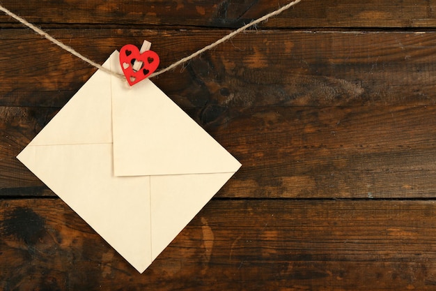 Love letter hanging on rope on rustic wooden background