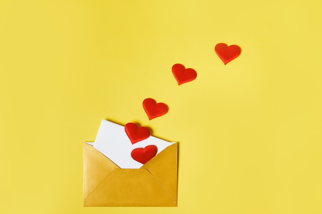 A love letter. An opened golden envelope with hearts and love letter inside. Saint Valentine Day concept.