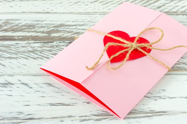 Love letter with paper heart on wooden background. Festive greeting card for St Valentines day.