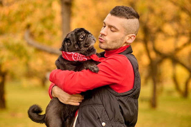 Love. A man standing in the park and hugging his dog