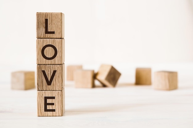 Love message written in wooden blocks on light background with blurred cubes