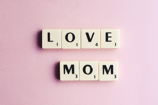 LOVE MOM word on wooden cubes on a pink background