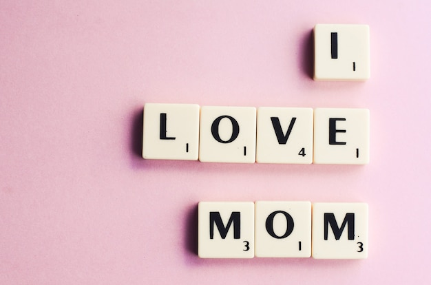 LOVE MOM word on wooden cubes on a pink background