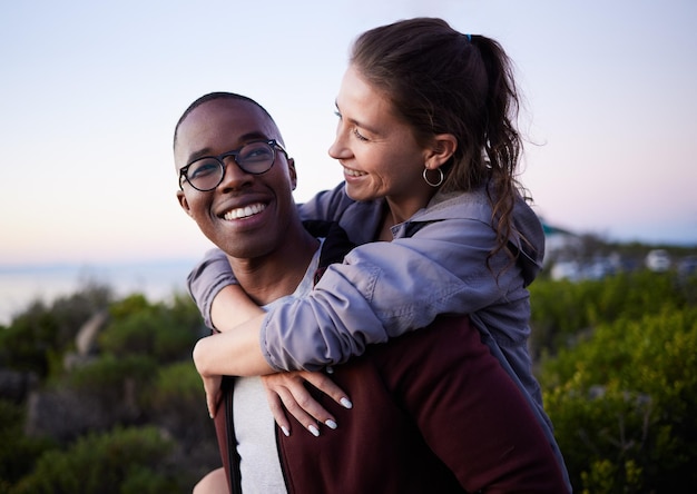 Love nature and interracial couple piggyback on mountain adventure for holiday vacation and hiking on weekend Travel dating and happy man carry woman enjoying calm outdoor freedom and peace