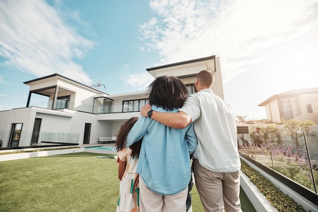 Love new home and family standing in their backyard looking at their property or luxury real estate Embrace mortgage and parents with their children on grass at their house or mansion in Canada